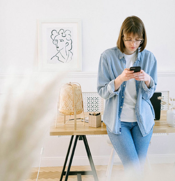 Young woman consulting the assistant on her phone at a desk