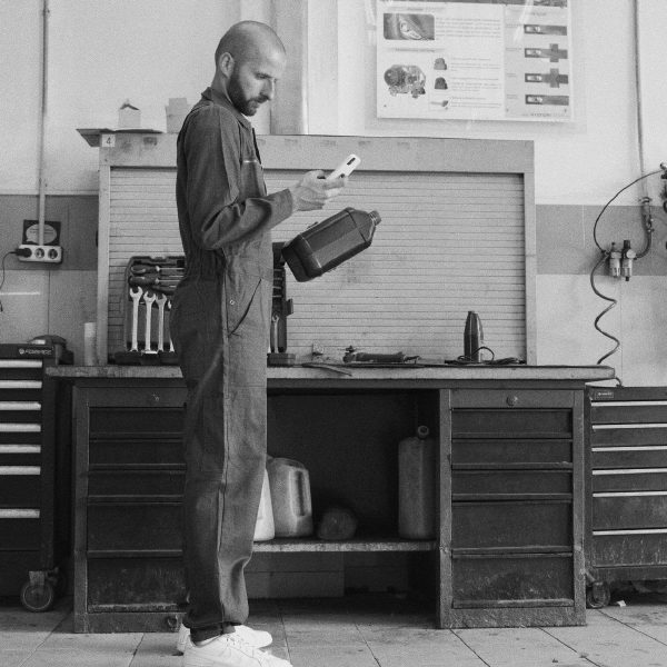 Mechanic in a workshop checking his phone while holding an oil canister